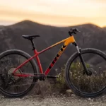 A red and yellow mountain bike , with a mountain range in the background. The bike is a Trek Marlin 7 model.