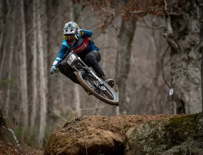 Mountain biker makes a steep jump on a forest road