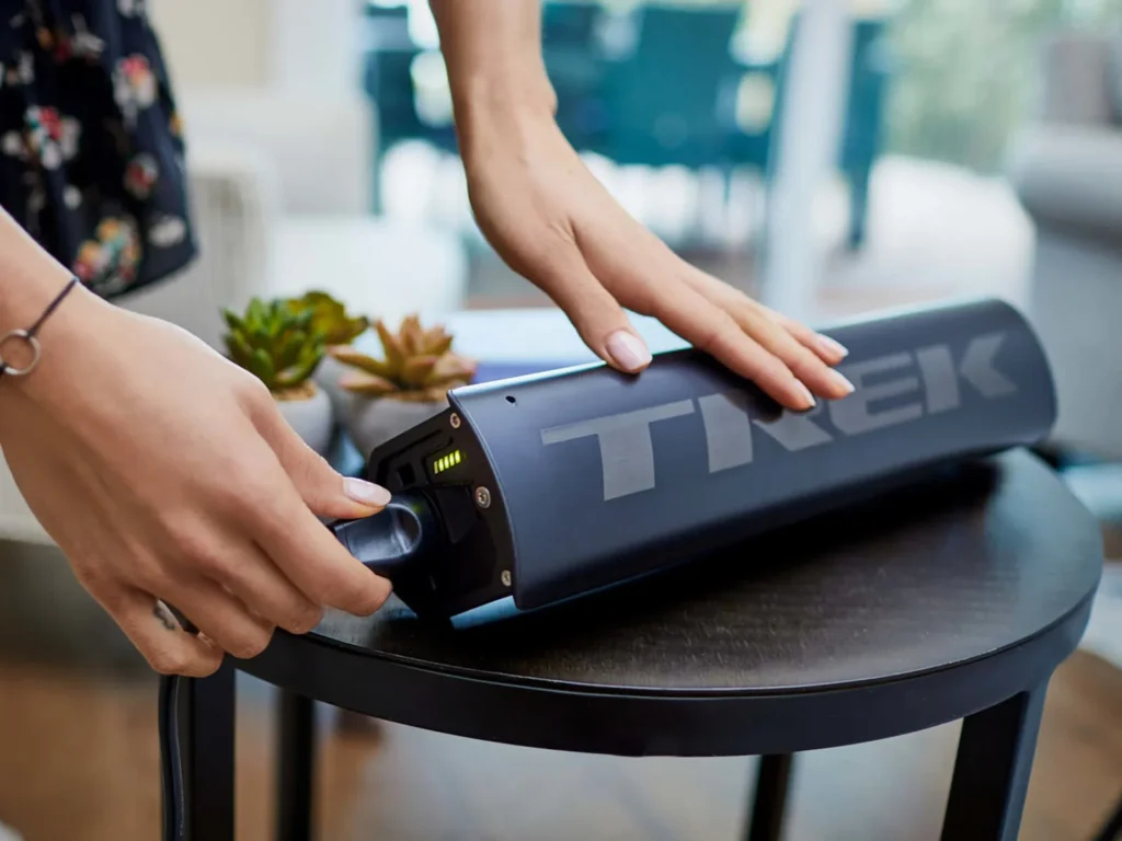 A person plugs in a Trek battery pack to charge