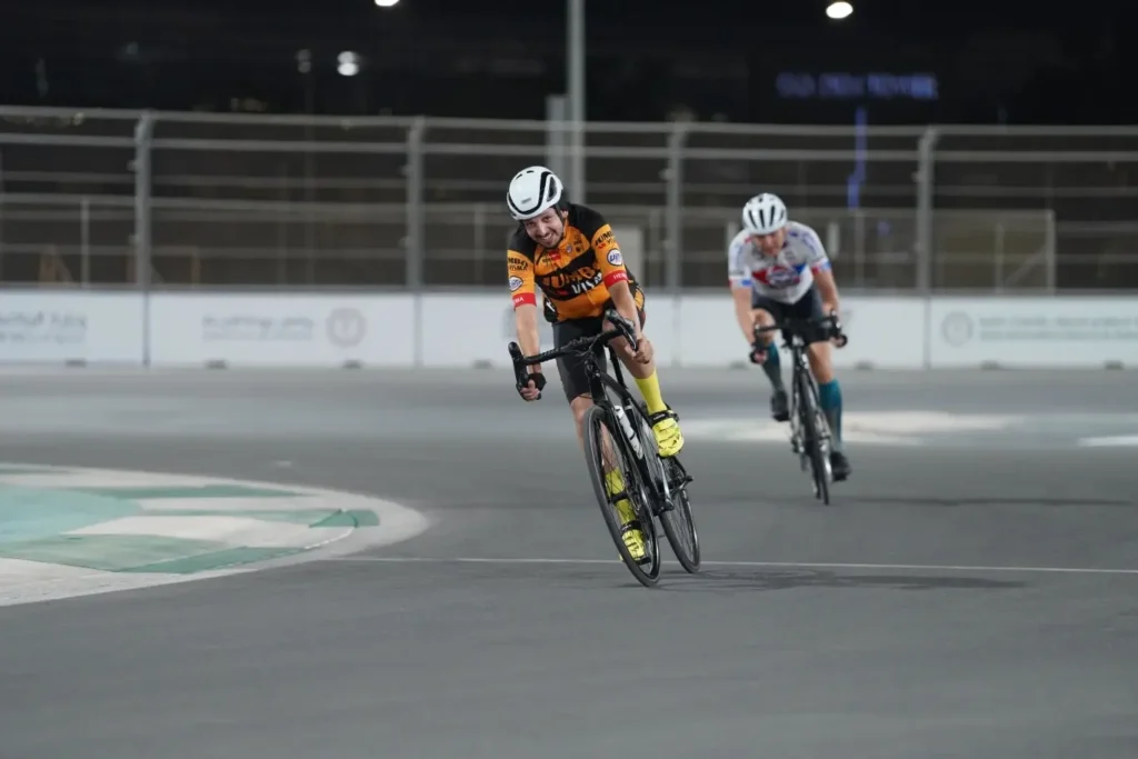 Two cyclists racing on a track at night.