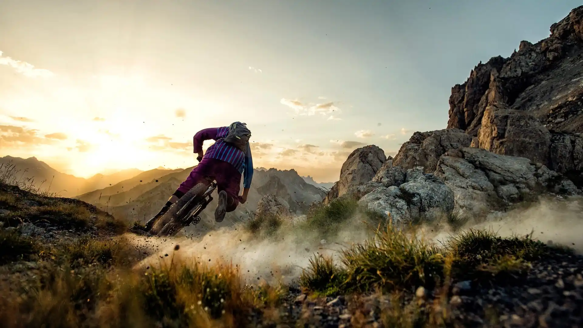 Cyclist riding a mountain bike at sunset on mountain slopesCyclist riding a mountain bike at sunset on mountain slopes