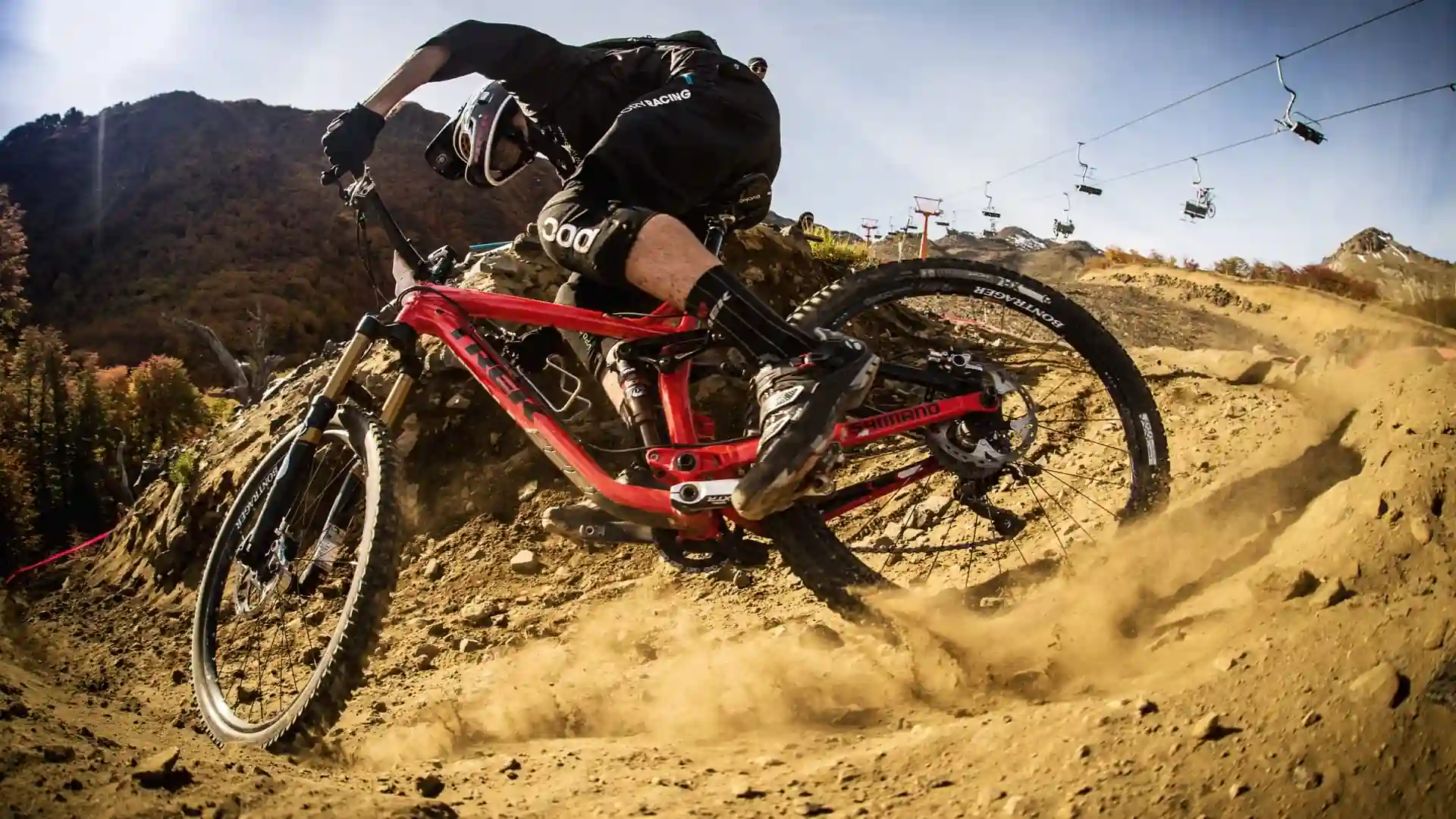 A cyclist riding a red Trek mountain bike on a dry, dusty trail