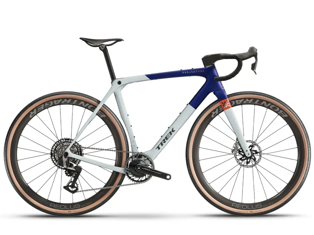 A white and blue Trek SLR 9 gravel bike with tan sidewall tires, leaning against a white background