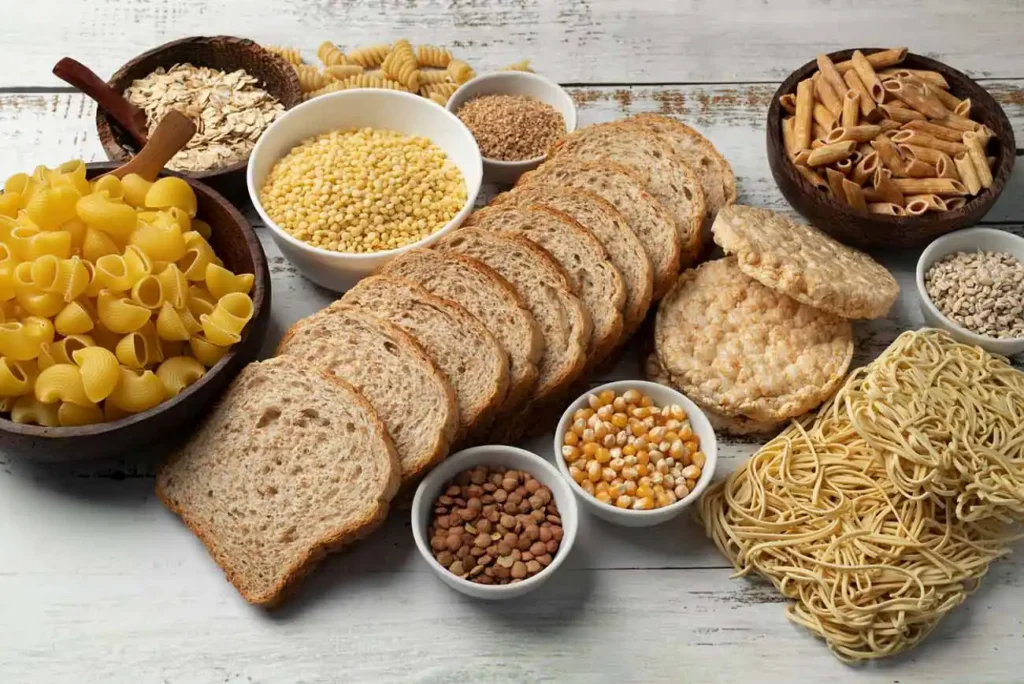 Flat of various carbohydrate-rich foods including pasta, bread, grains, and corn