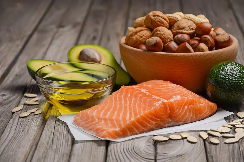 Ingredients for a healthy meal: salmon, avocado, nuts, and oil in a glass bowl.