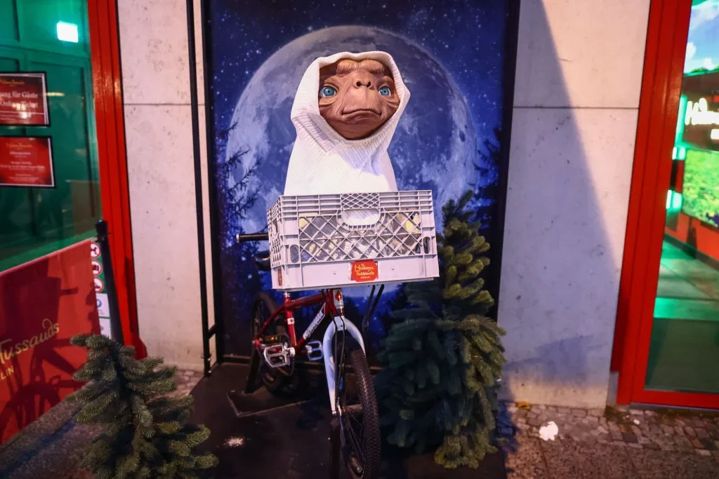 A statue of E.T. on a bicycle in front of a moon backdrop