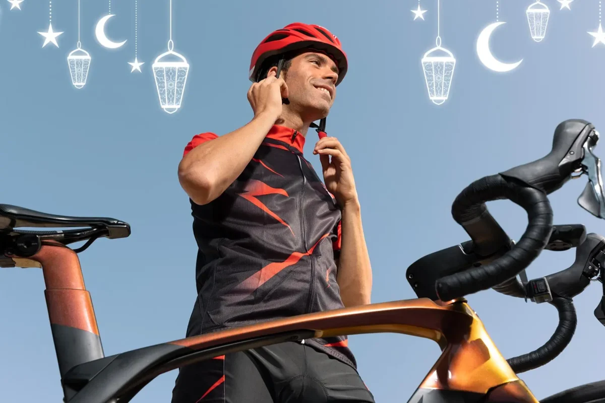 A cyclist stands beside their bicycle They wear a red helmet and a black and red cycling jersey