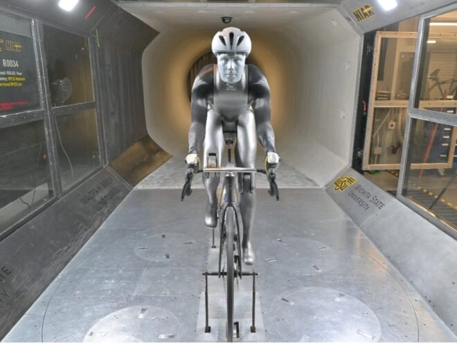 The robot 'Manny' rides a black bike in a wind tunnel, mimicking a cyclist's movements to test aerodynamics and performance