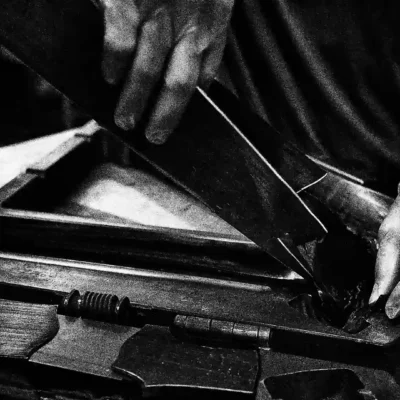 The image shows a person's hand working on a bicycle component, which is likely a frame made of carbon fiber.